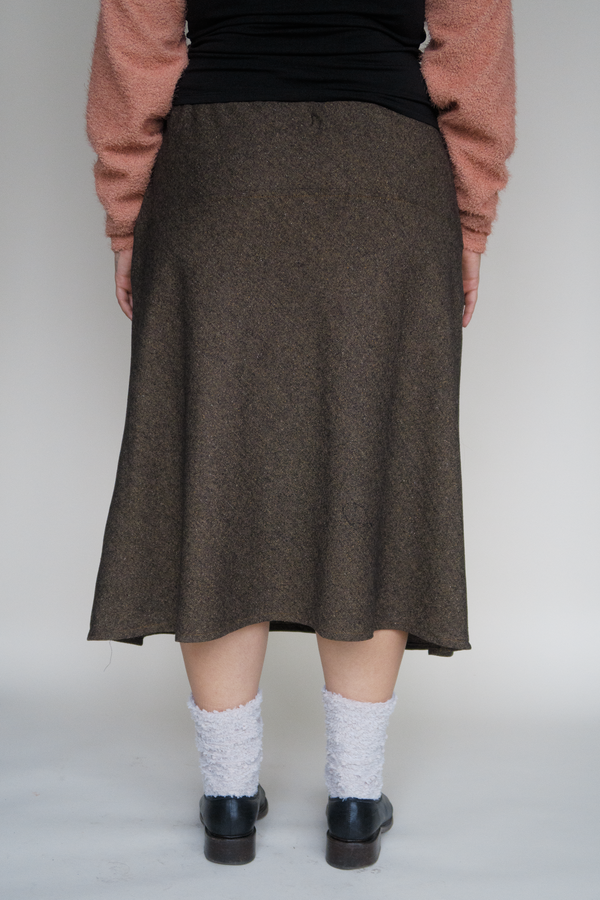 A confident plus size woman wearing long brown wool skirt, white fuzzy socks and black loafers