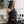 Load image into Gallery viewer, young woman standing in fashion studio wearing a Black one-shoulder tank top, with a band that crosses over the chest and arm. Design by Alex Watson Studio.
