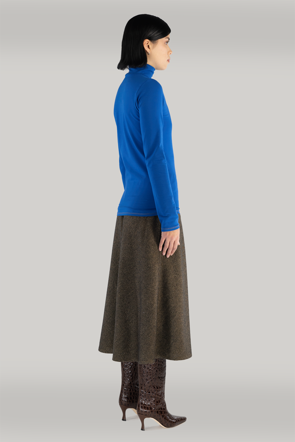 woman standing with cobalt blue turtleneck long sleeve and long maxi brown wool skirt and maroon boots